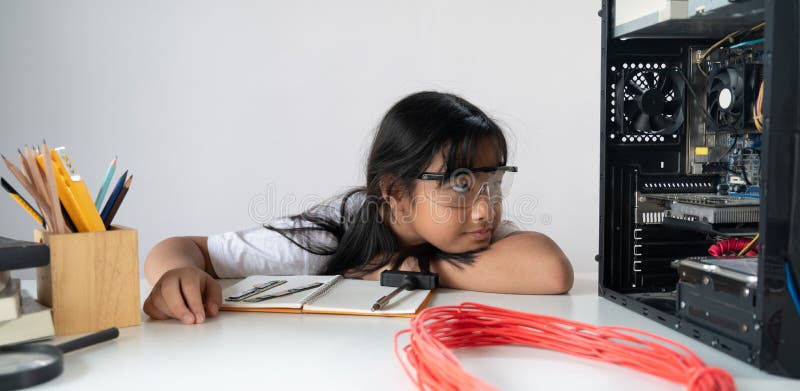 A little girl is repairing computer hardware at the white working table royalty free stock images