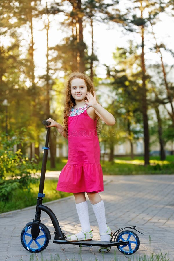 Little Girl is Riding a Scooter in the Park. Stock Photo Image of