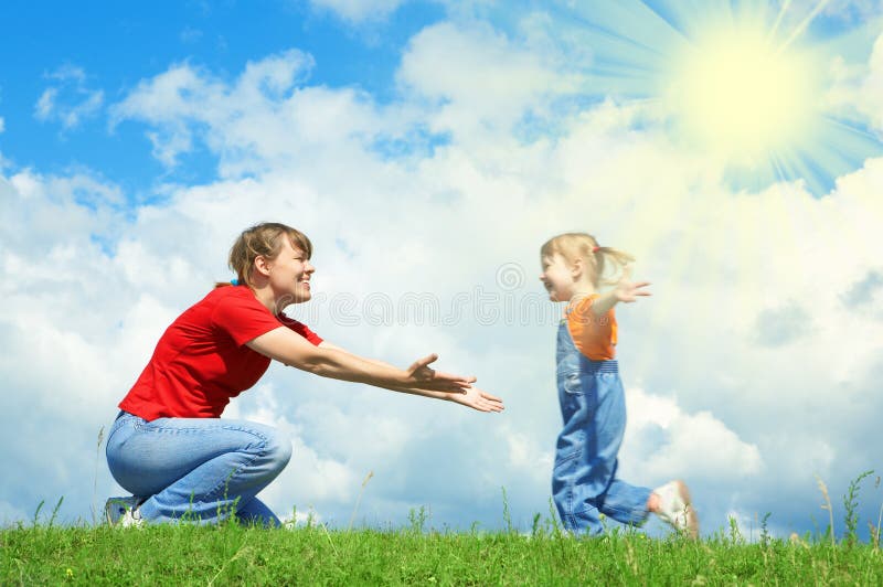 Little girl run to mother embrace on green grass