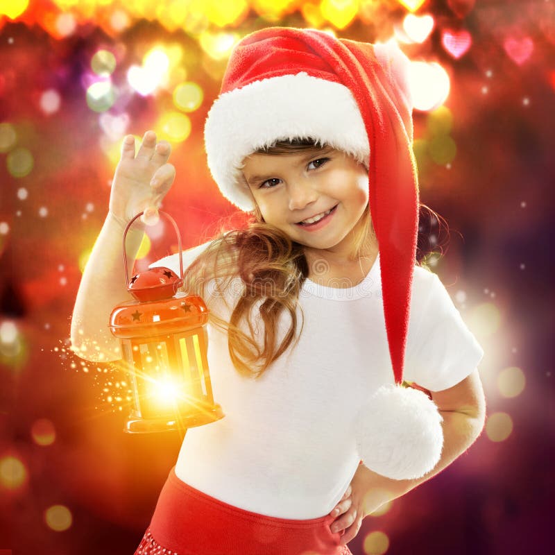 Little girl in Santa hat holding red Christmas