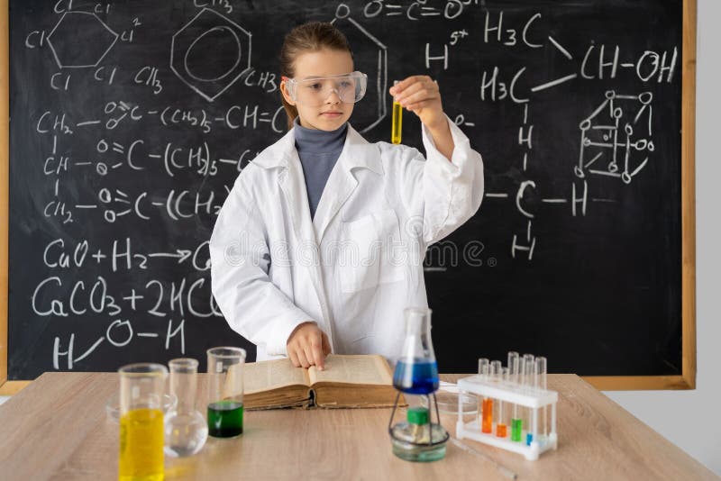 Little girl scientist examining test tube with chemical reagent. Schoolgirl making experiment in chemistry class. Research and education in school. Chemical laboratory with glass flasks.