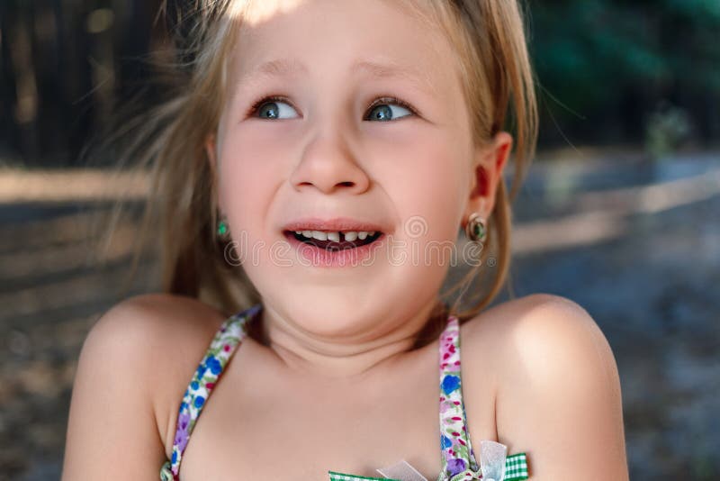 A little girl shows a wobbly baby tooth in her mouth