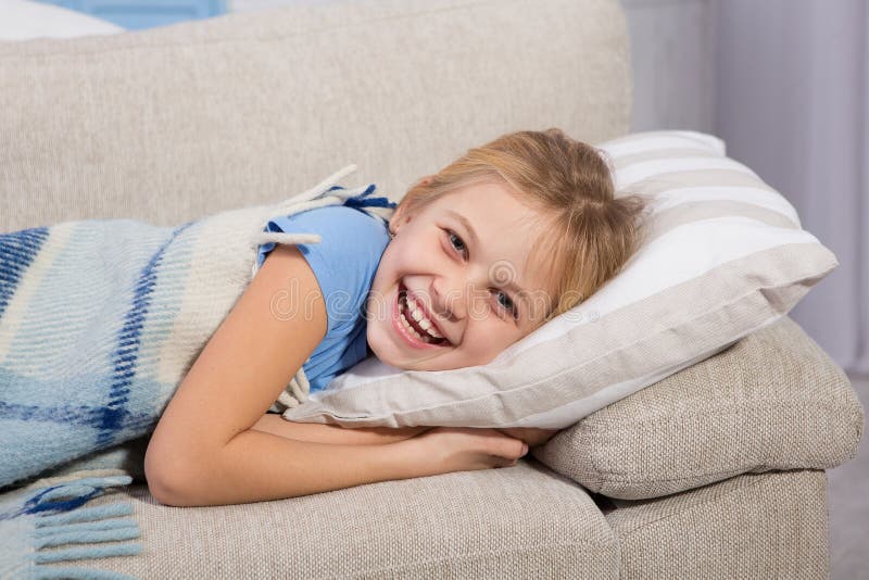 Little girl, sick lying on sofa and smiling. royalty free stock photo Little girl, sick lying on sofa and smiling. royalty free stock photo