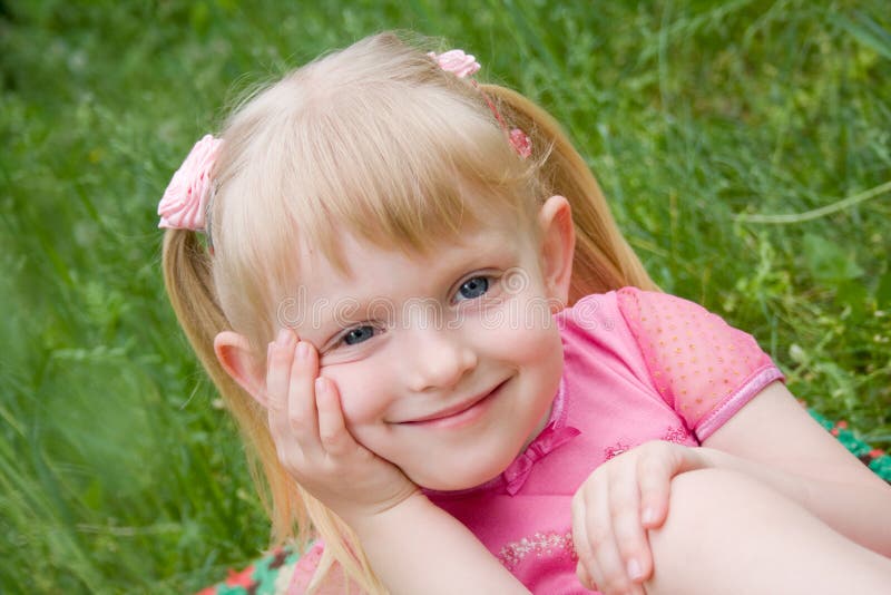 Little girl sits on a grass