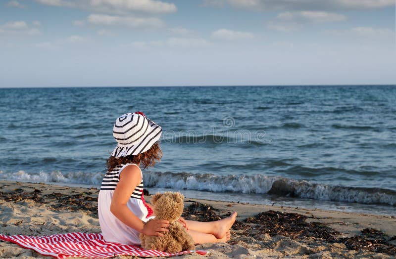 8 Year old girl sitting on beach at dusk Stock Photo