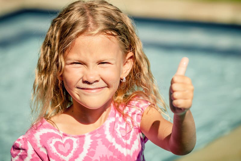 Little girl sitting near swimming pool