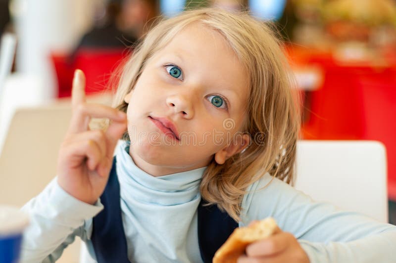 Little girl sitting at a table while eating threatens with her finger stock photos