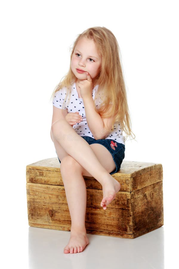 A little girl is sitting on a wooden box. stock image A little girl is sitting on a wooden box. stock image