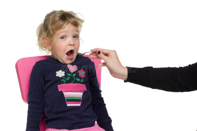 Little girl with spoon in opened mouth