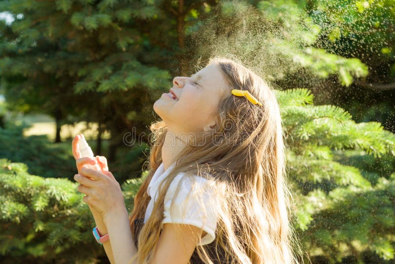 Little girl spraying face with thermal water. Joy and enjoyment on a hot sunny day stock photo Little girl spraying face with thermal water. Joy and enjoyment on a hot sunny day stock photo