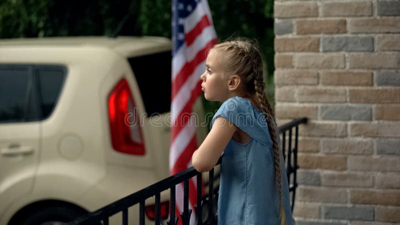 Little girl standing at house terrace, waiting for parents, solitude concept