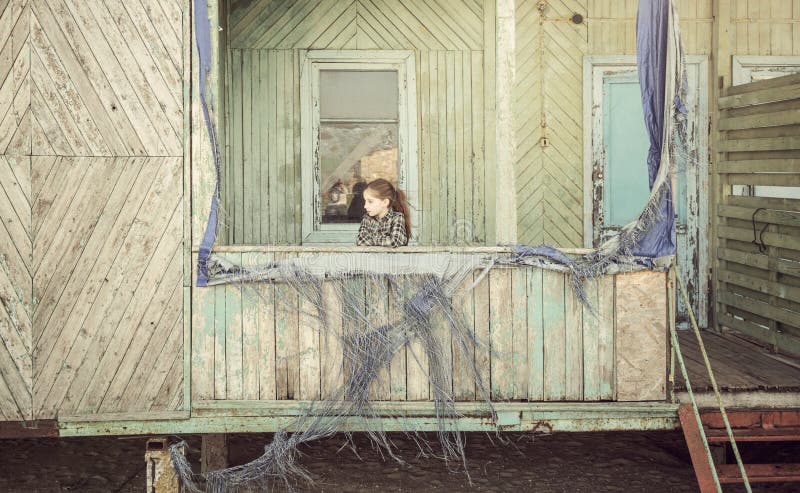 Little girl standing on porch of abandoned cabin