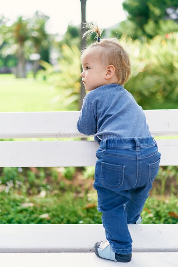 Little Girl Stands Leaning on a White Wooden Fence in the Park Stock ...