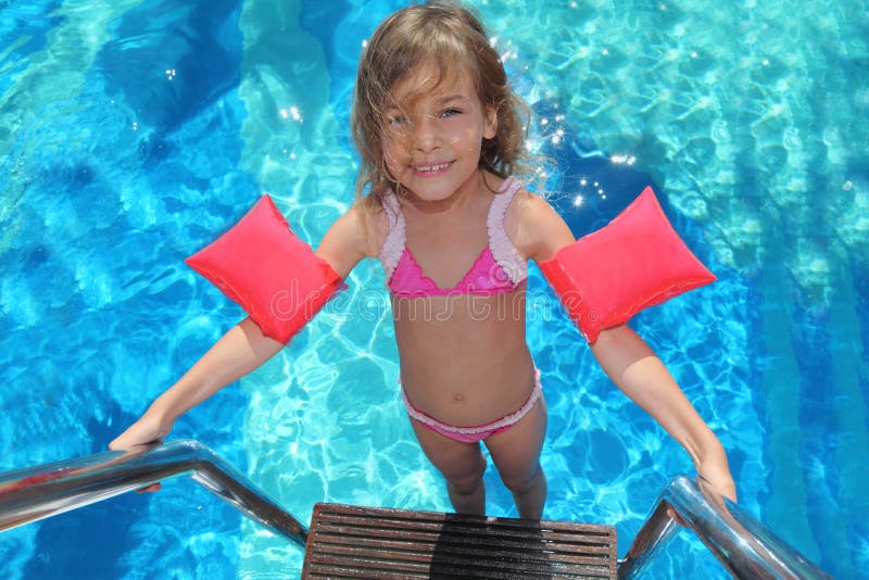 Little girl stands on stairs in pool