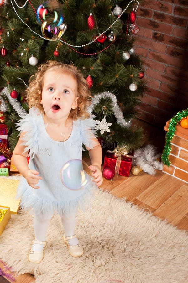 Little girl staying near Christmas tree