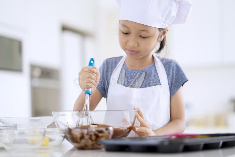 Little girl stirring cookie dough on the bowl royalty free stock image Little girl stirring cookie dough on the bowl royalty free stock image
