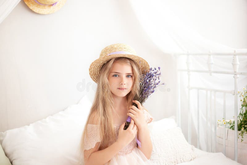 Little girl in a straw hat and dress on a background of a bright white bedroom with a rustic interior. Childhood concept. Provence royalty free stock images Little girl in a straw hat and dress on a background of a bright white bedroom with a rustic interior. Childhood concept. Provence royalty free stock images