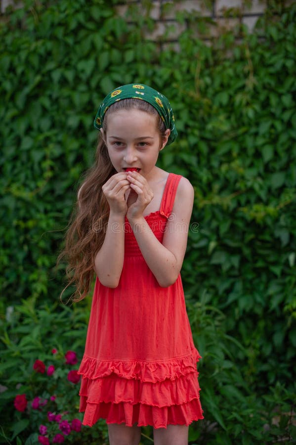 Little girl on the street against a background of green foliage. Girl with long hair. Child 9-10 years old