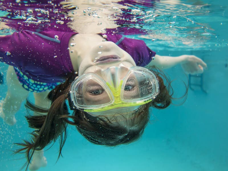 Bambina di divertirsi e di nuoto a testa in giù in acqua.