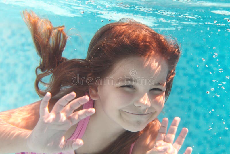 The little girl swimming underwater and smiling