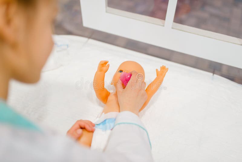 Little girl in uniform feeding toy doll, playroom stock photography Little girl in uniform feeding toy doll, playroom stock photography