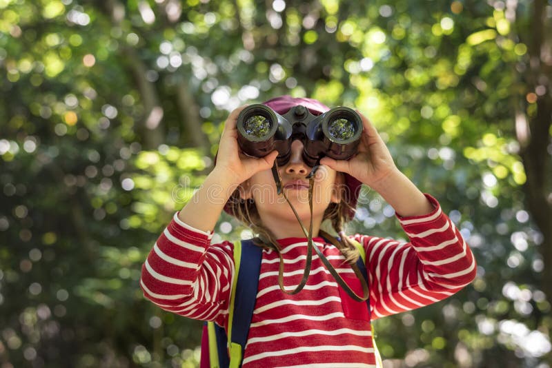 Little girl using binoculars in the forest