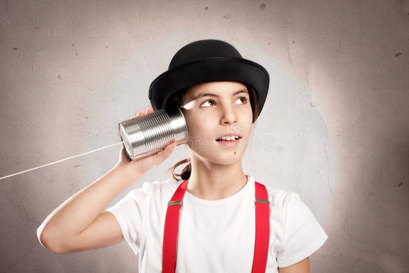Little girl using a can as telephone stock image Little girl using a can as telephone stock image