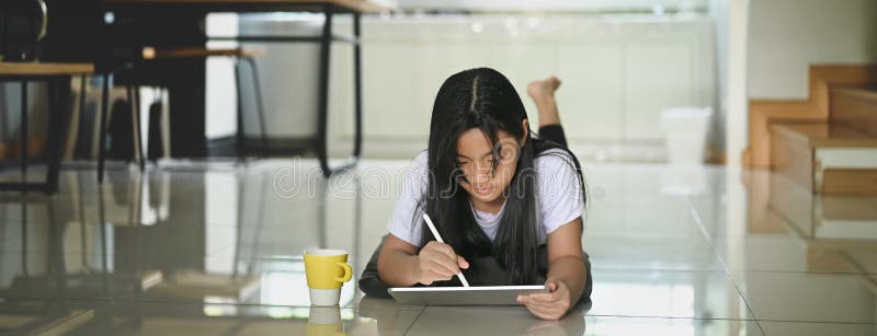 A little girl is using a computer tablet and stylus pen. stock image