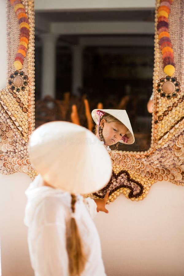 Little girl in Vietnameese touching traditional vietnameese mirror made with shells royalty free stock photography Little girl in Vietnameese touching traditional vietnameese mirror made with shells royalty free stock photography