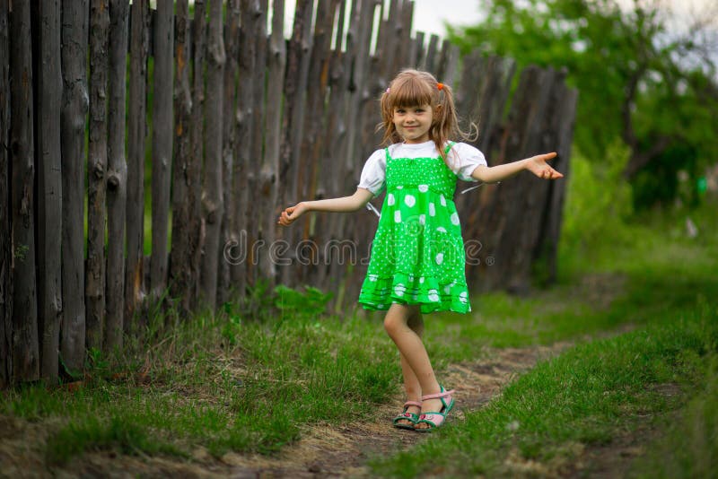 Little girl walk in green garden in summer day