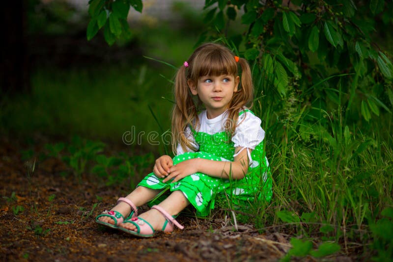 Little girl walk in green garden in summer day