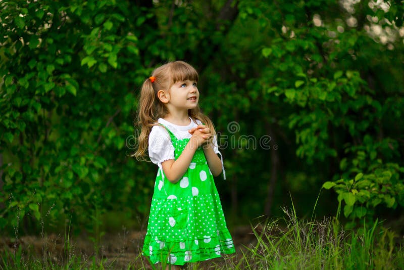 Little girl walk in green garden in summer day