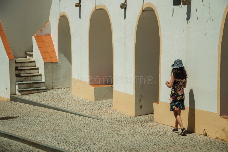 Little girl walking on sidewalk next to building with arches