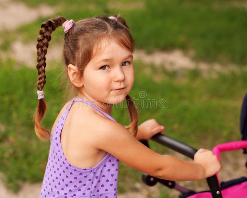 Little girl walking with a toy stroller.