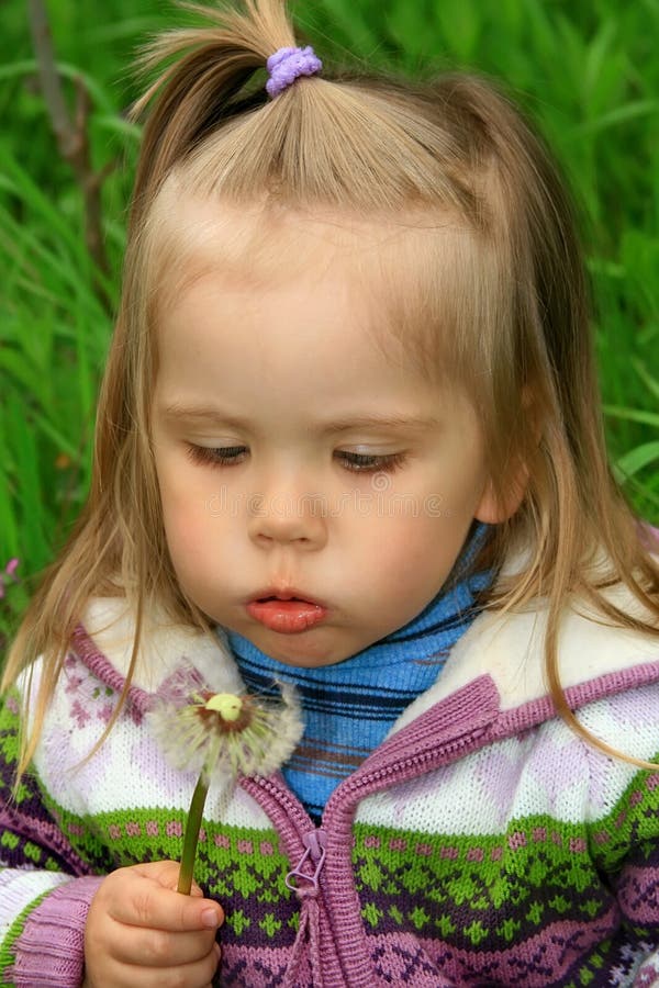 Little girl walks in the spring on a young grass