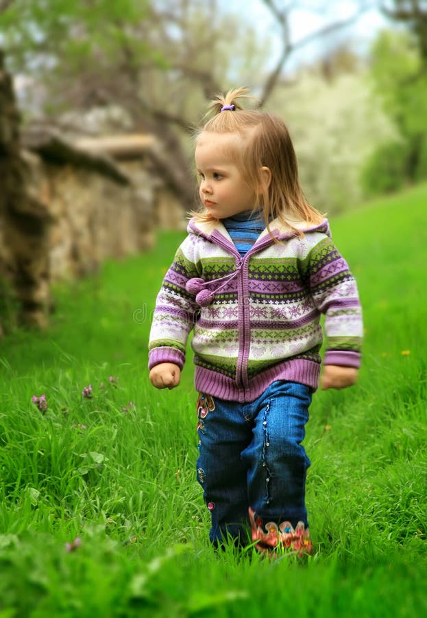 Little girl walks in the spring on a young grass