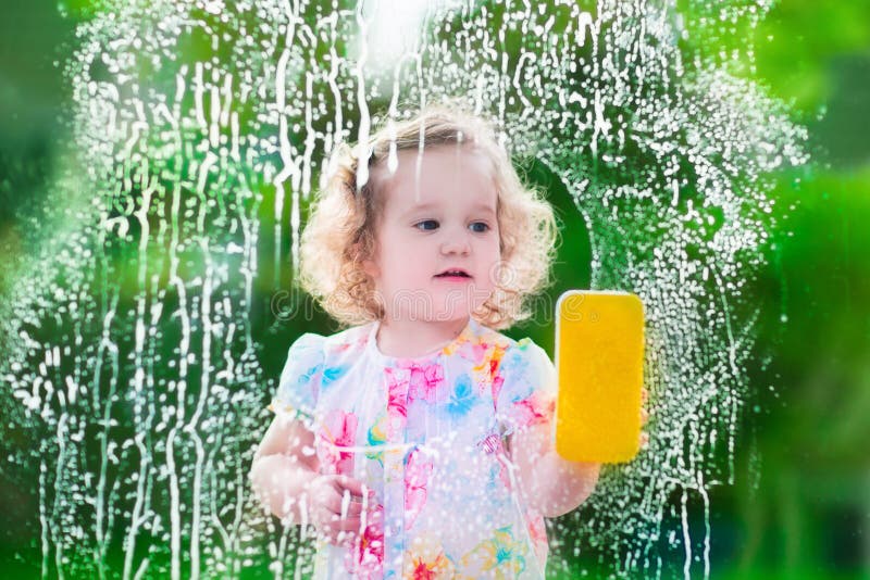 Little girl washing a window