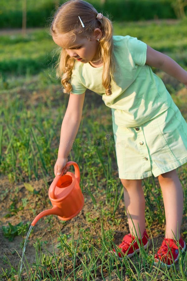 Little girl watering the onion seedlings