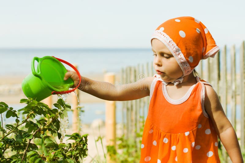 Little girl watering plants with water