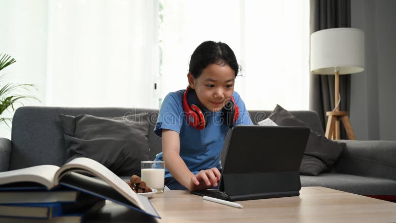 Little girl wearing headphones sitting on sofa and using digital tablet. stock photography