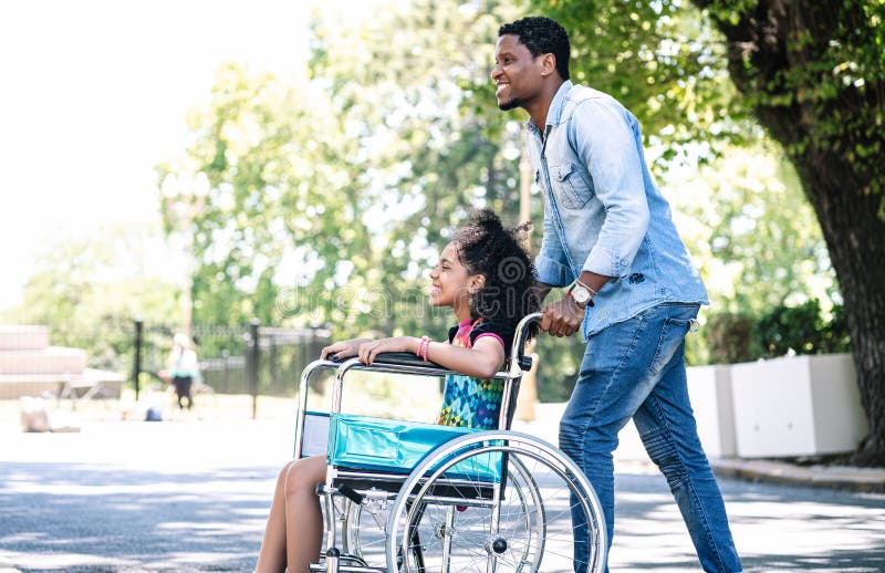 Little girl in a wheelchair enjoying a walk with her father.