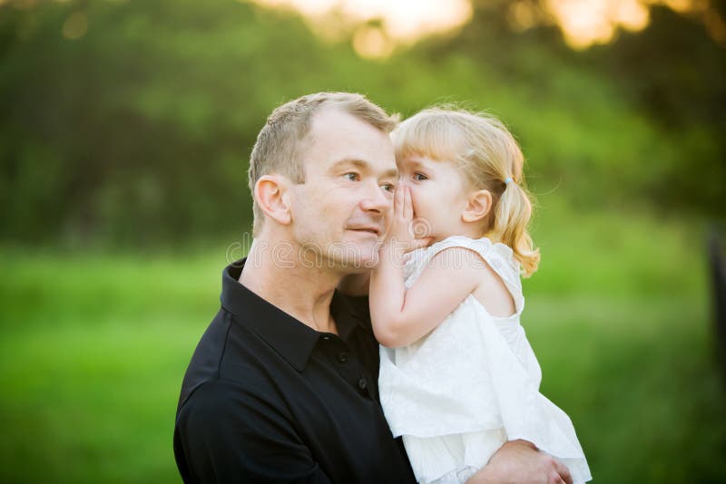 This little girl is whispering a secret in her dad's ear. 
