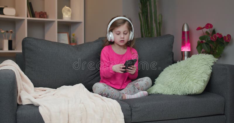 Little girl in wireless headphones dancing and moving to the rythm. Kid in headphones. Happy little girl listening to