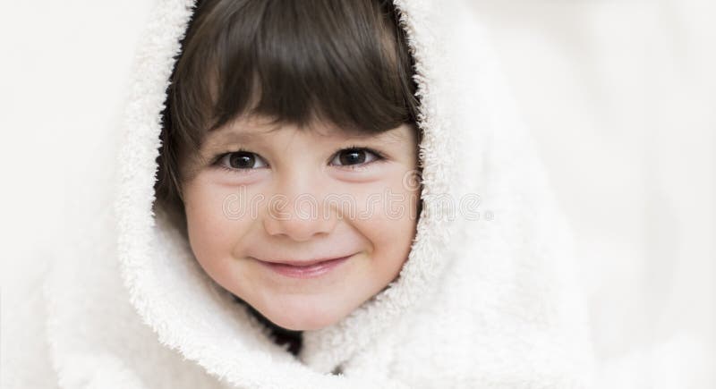 Ritratto di una bambina, con la testa avvolta in un asciugamano bianco.