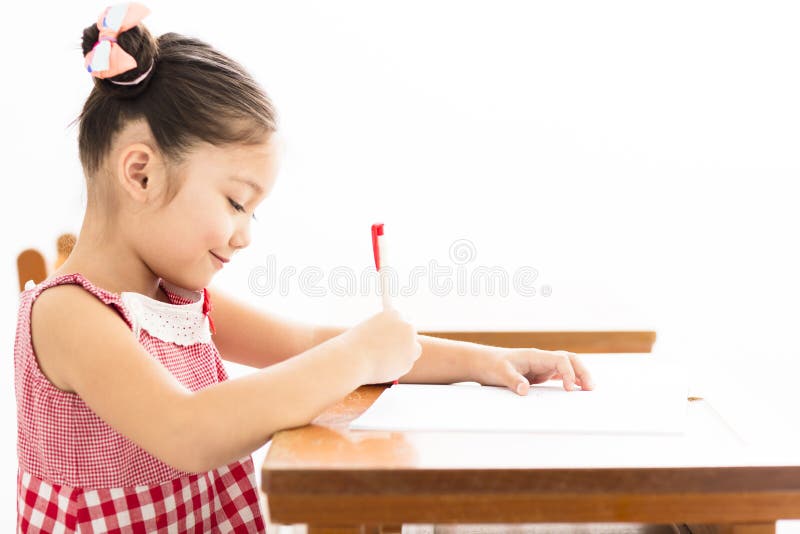 Cute Little Girl is Writing at the Desk in Preschool Stock Image