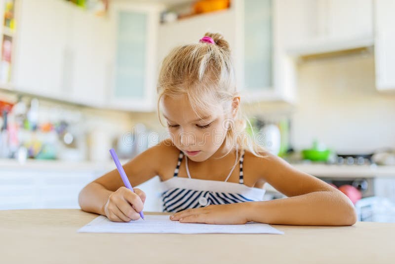 Little girl writing with pen in notebook stock photography