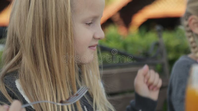 Little girls eating delicious desserts at the cafe