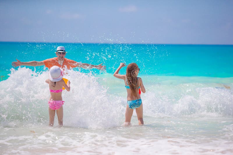 Little girls and happy dad having fun on the seashore swimming and running royalty free stock images Little girls and happy dad having fun on the seashore swimming and running royalty free stock images