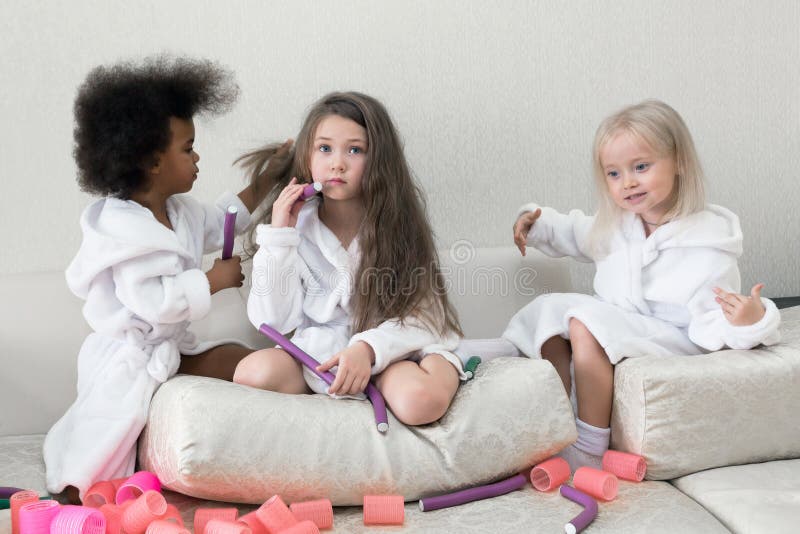 Little girls play with hair curlers and hairpins