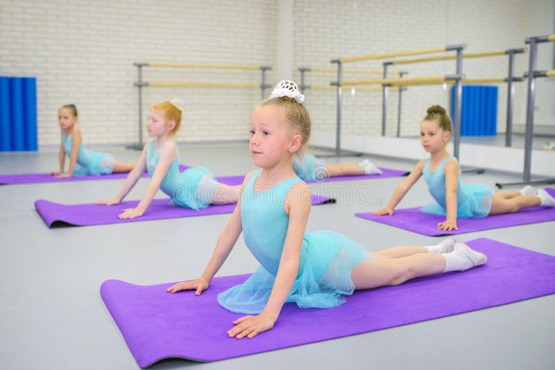 Little girls practicing ballet in studio, stretching on matts. royalty free stock photography